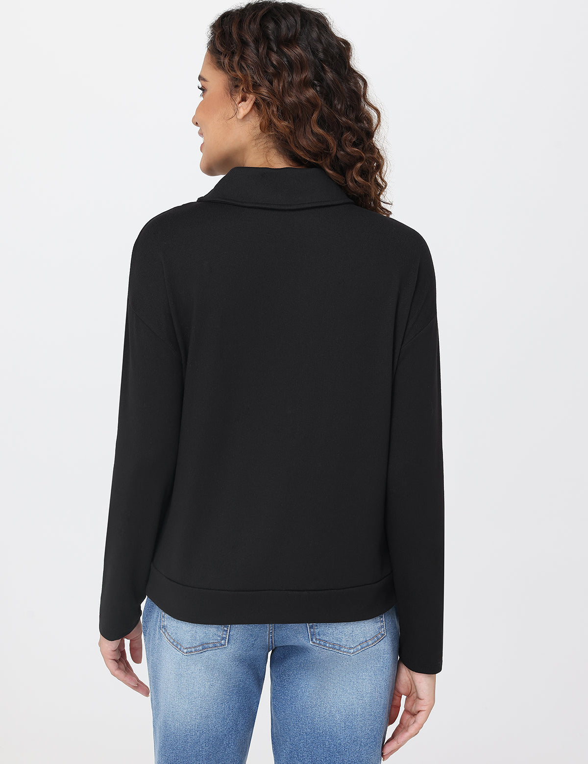 Woman wearing a black jacket and blue jeans on a white background