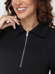 Close-up of a person wearing a black zip-up garment with a neutral background