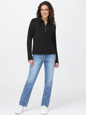 Woman wearing a black long-sleeve top and blue jeans on a white background