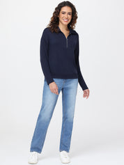 Woman wearing a navy long-sleeve top and light blue jeans on a white background