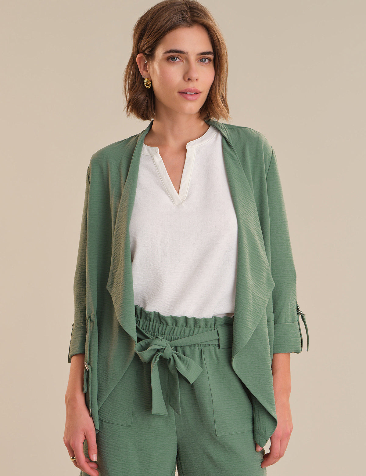 Woman wearing a green outfit with a white top against a beige background