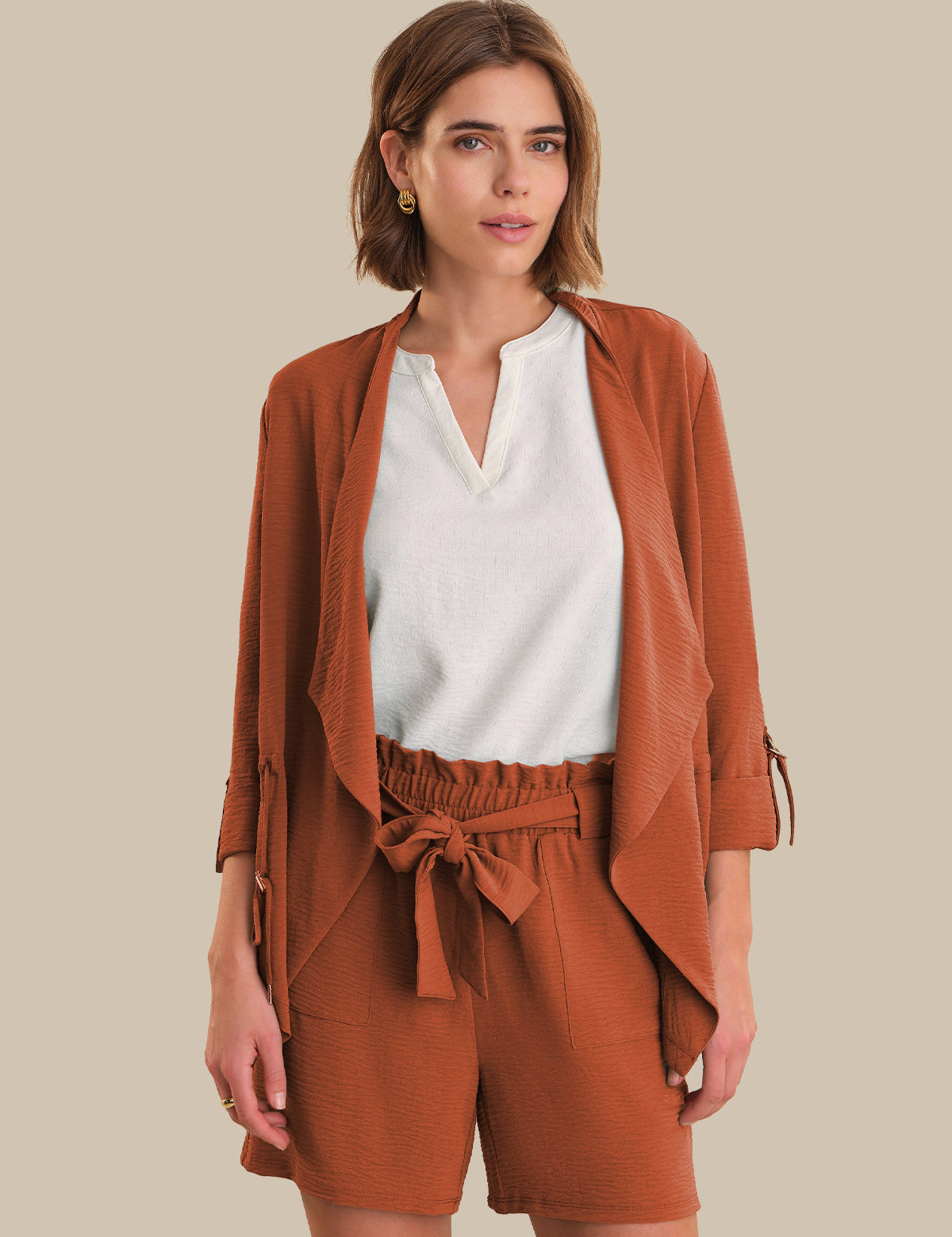 Woman wearing a brown outfit with a white top on a beige background