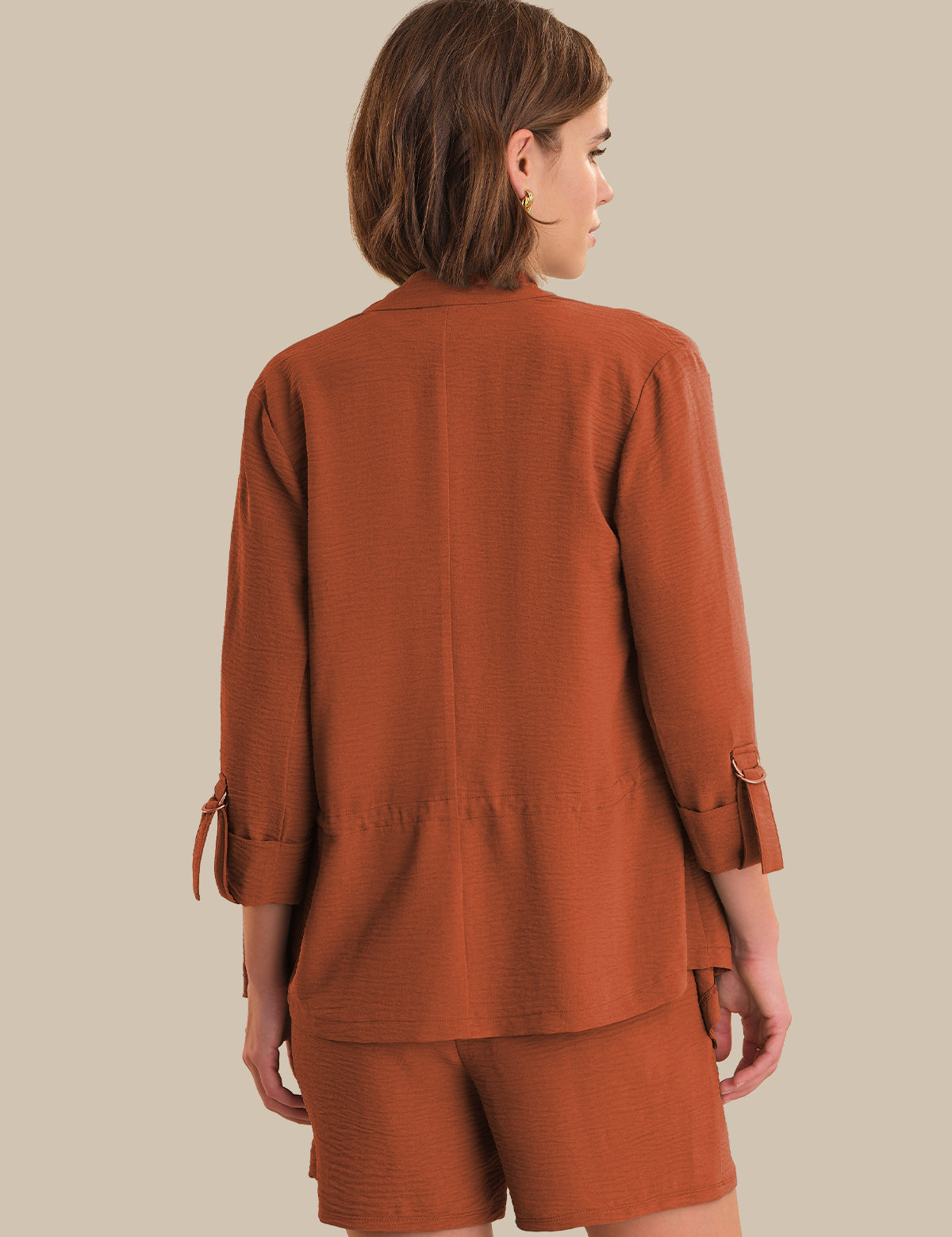 Person wearing a brown outfit on a beige background
