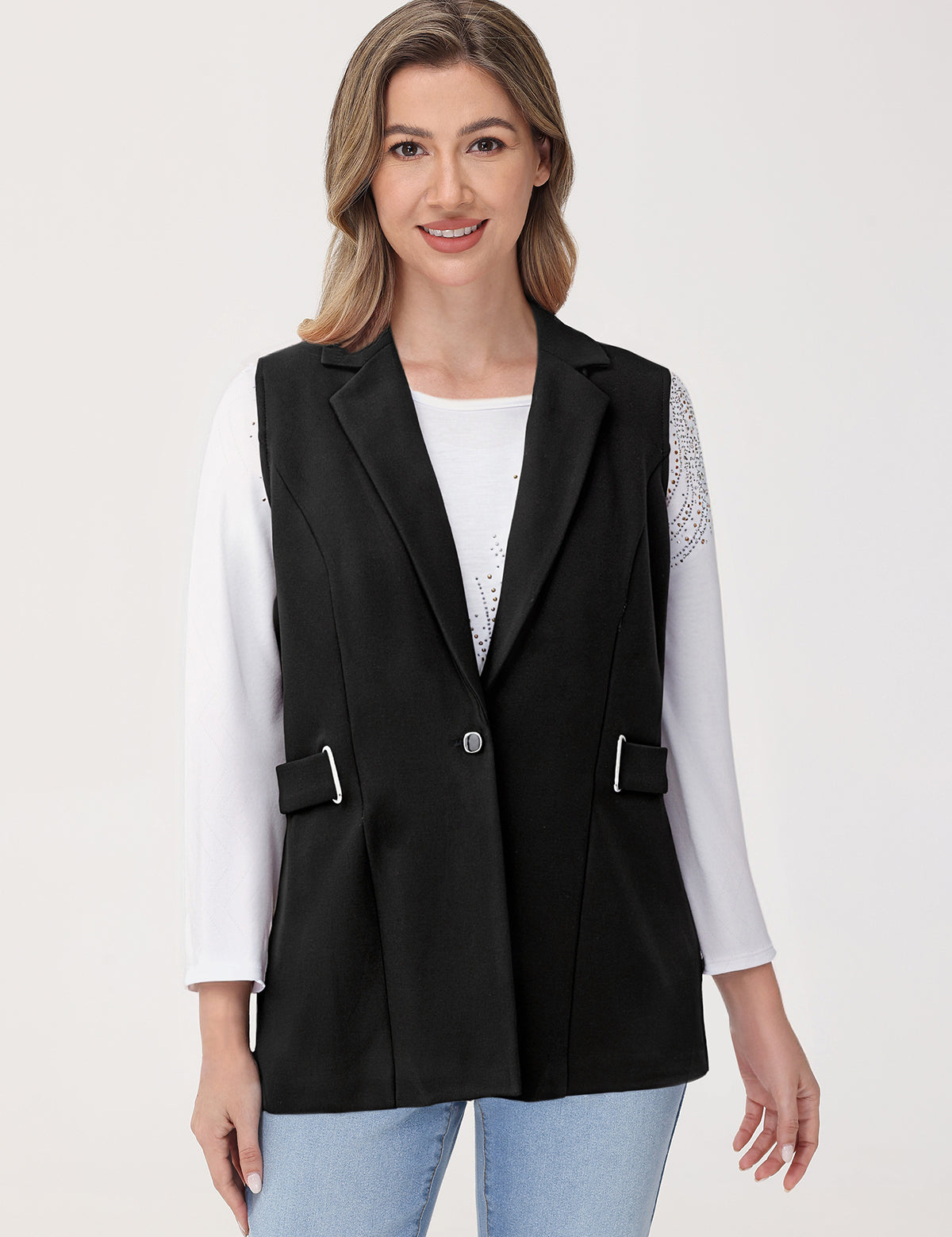 Woman wearing a black vest over a white shirt on a light gray background