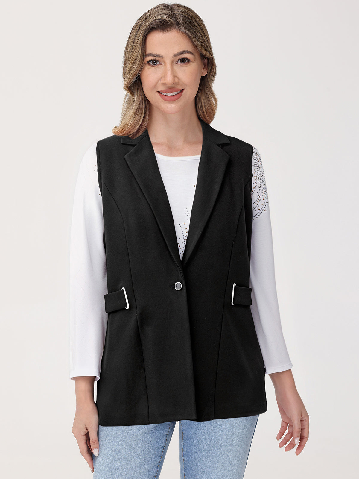 Woman wearing a black vest over a white shirt on a light gray background