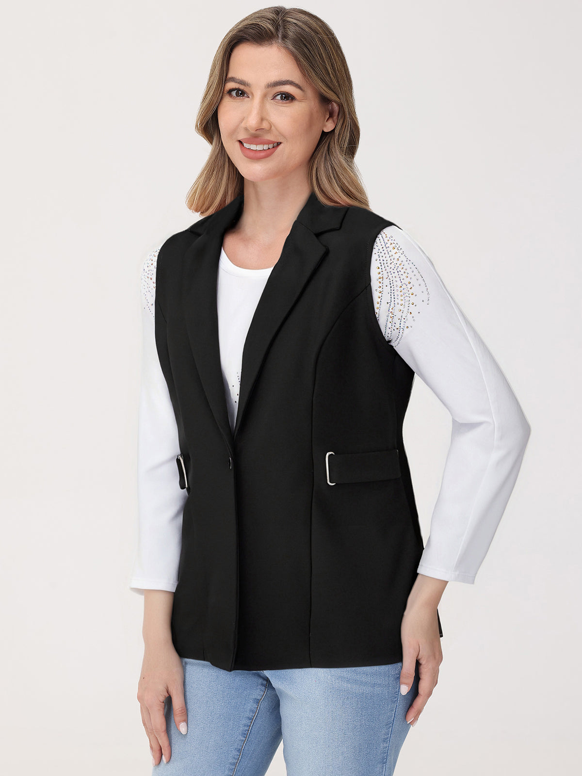 Woman wearing a black vest over a white shirt with a plain background