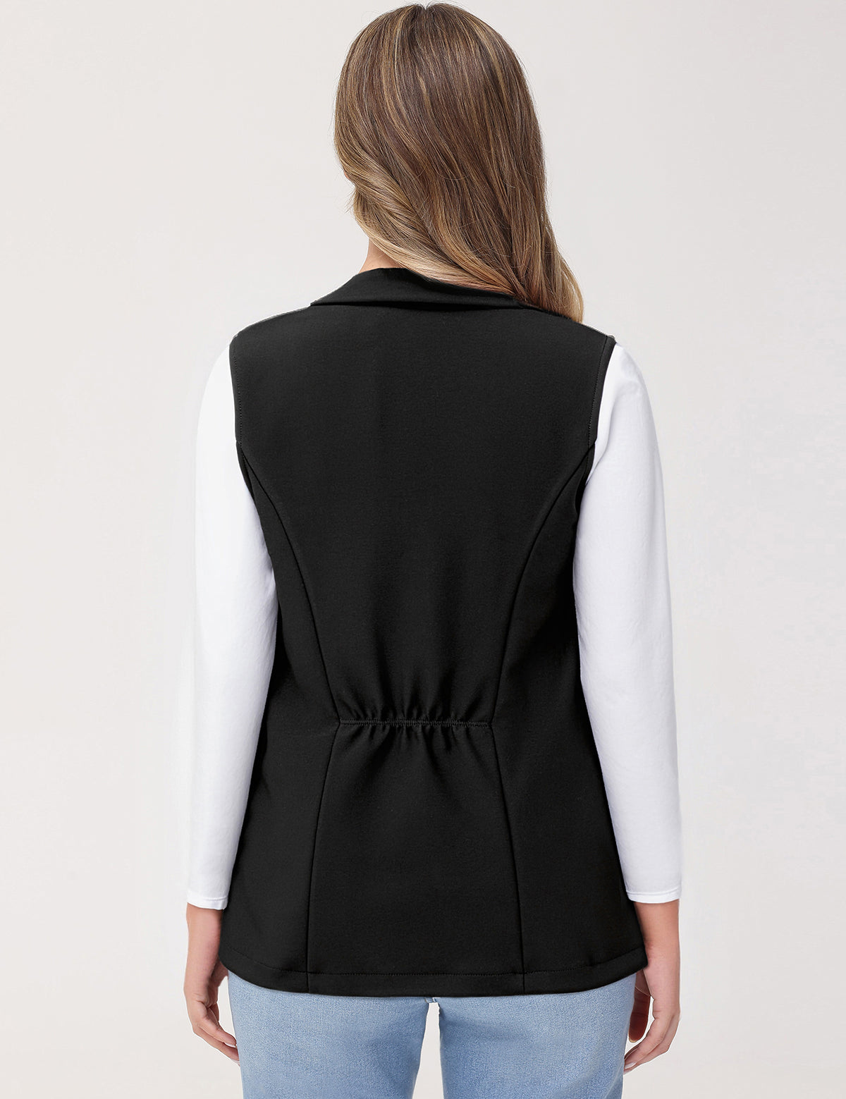 Person wearing a black vest over a white shirt on a light gray background