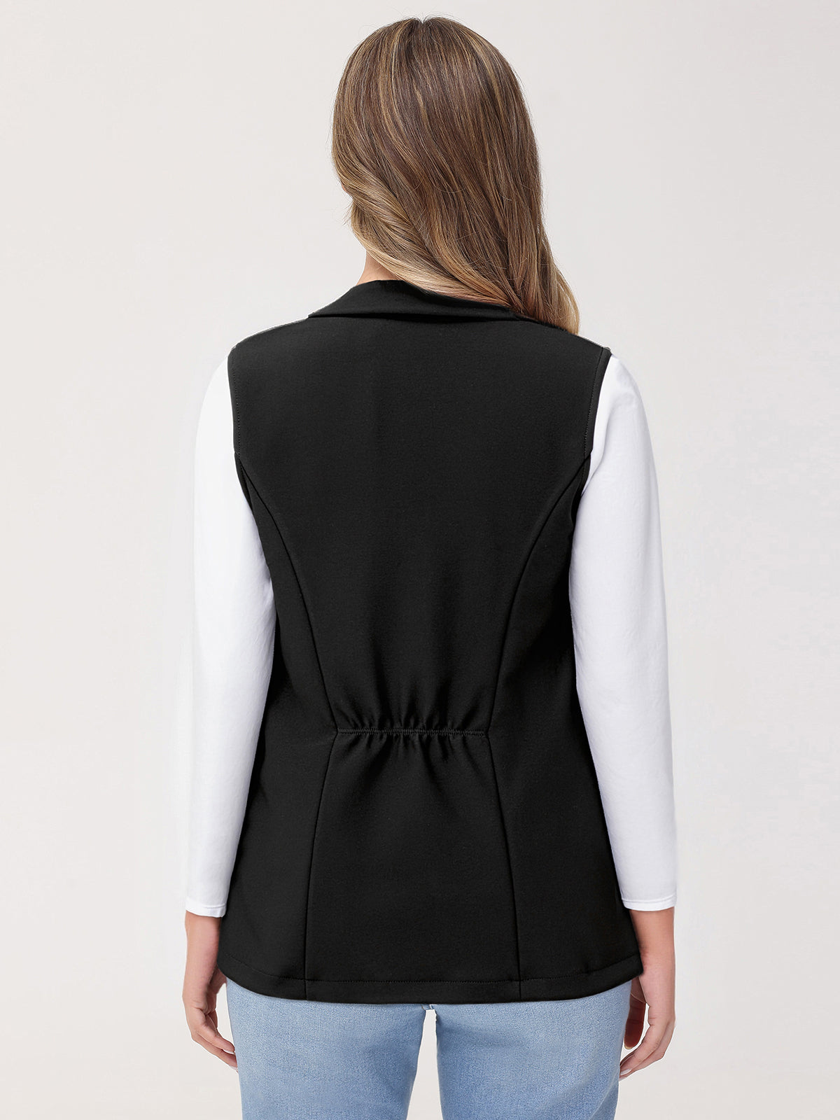 Person wearing a black vest over a white shirt on a light gray background