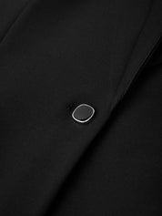 Close-up of a black fabric with a silver button on a dark background