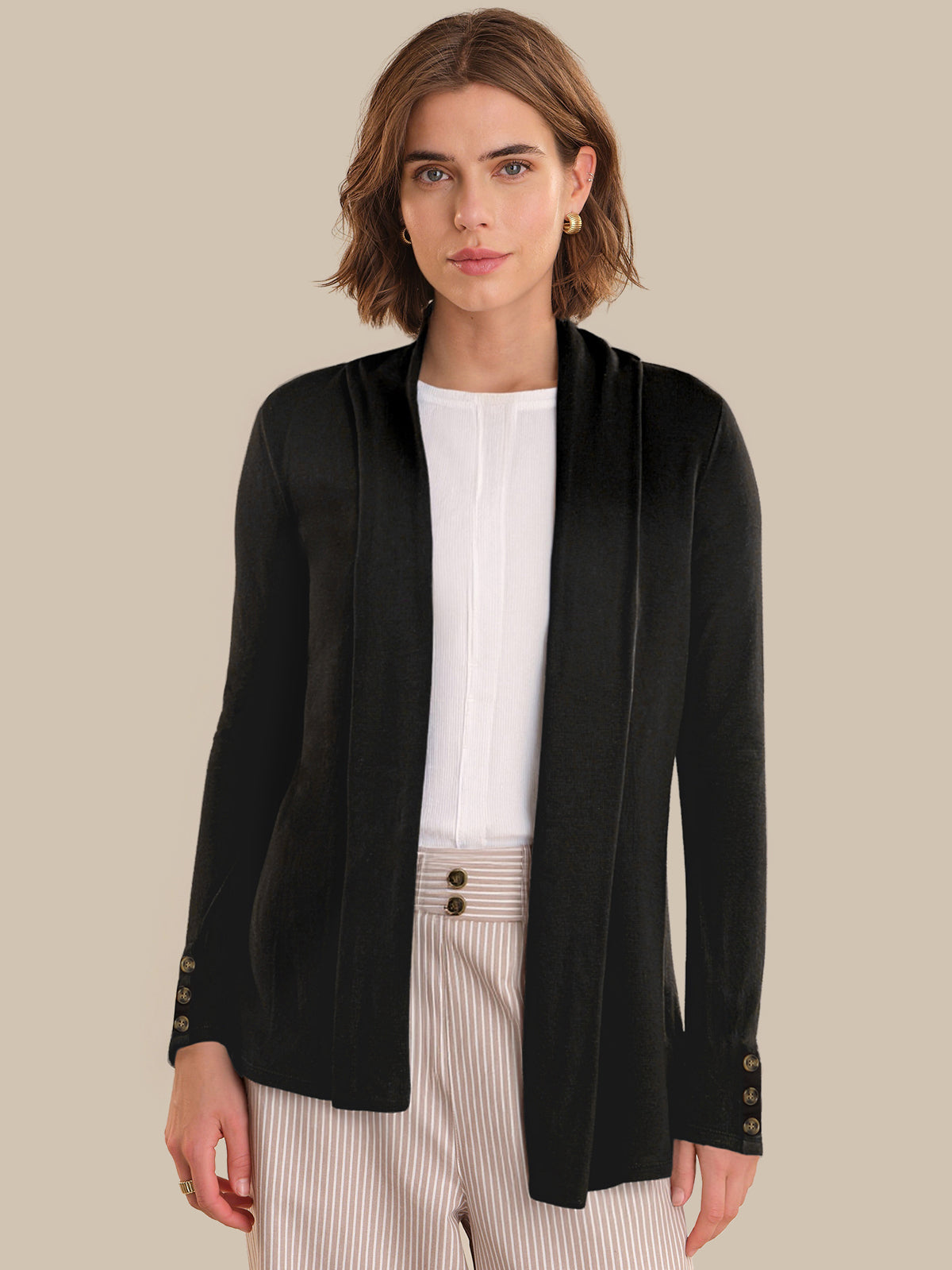 Woman wearing a black cardigan over a white shirt with a beige background