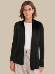 Woman wearing a black cardigan over a white shirt with a beige background