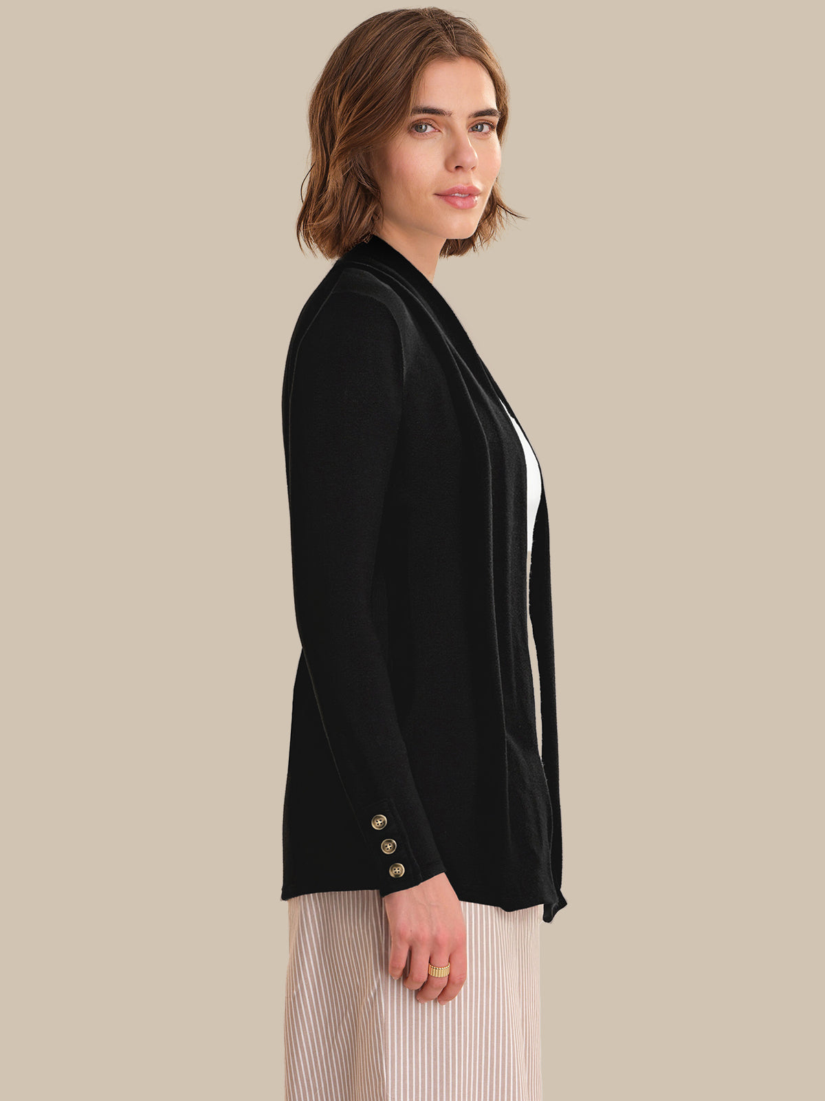Woman wearing a black cardigan with white trim on a beige background