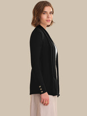 Woman wearing a black cardigan with white trim on a beige background