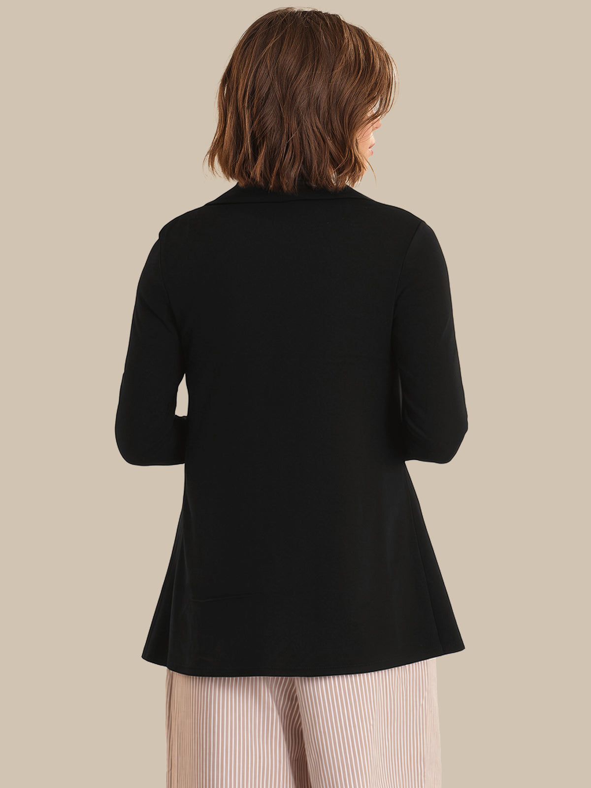 Person wearing a black cardigan on a beige background