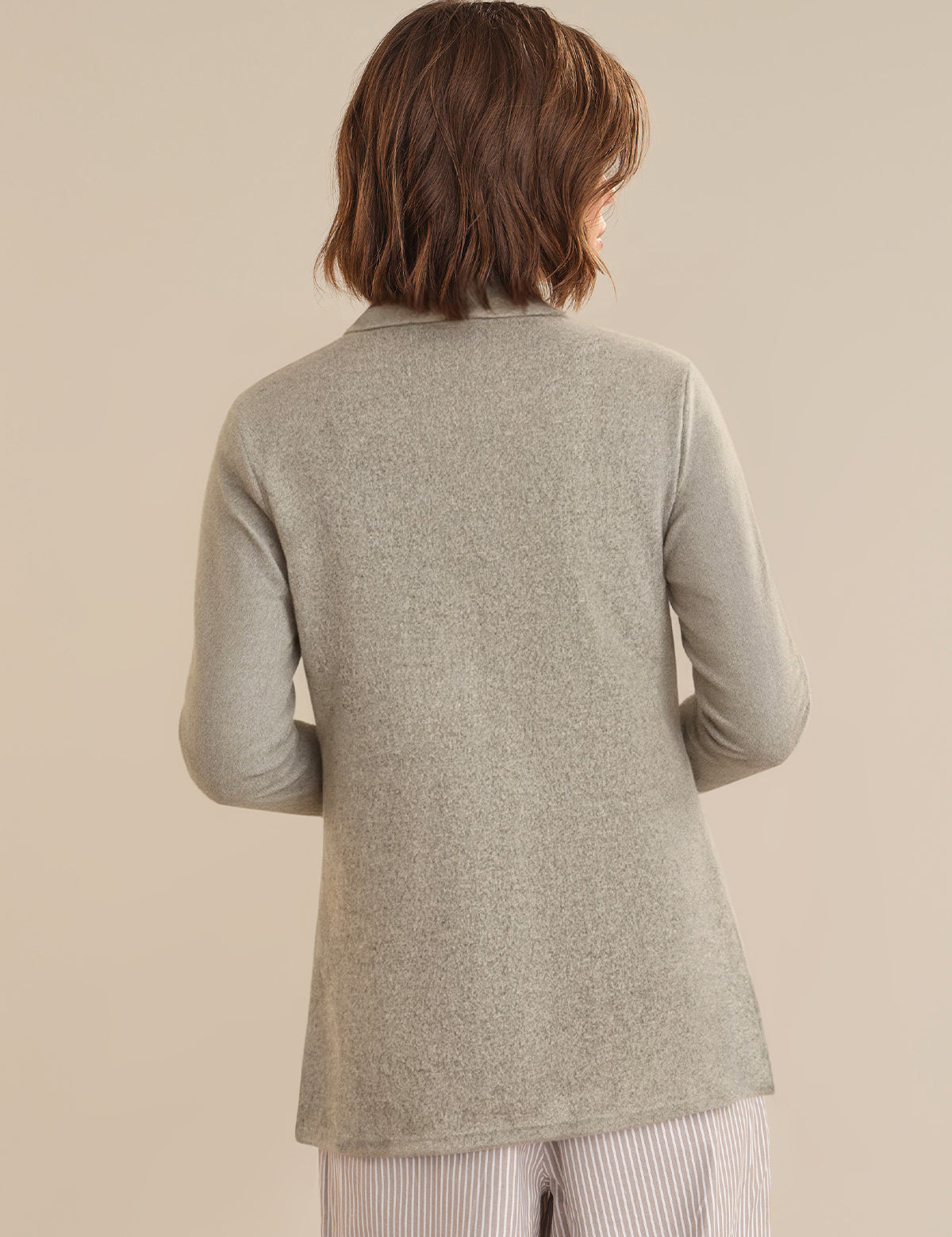 Person wearing a gray sweater against a beige background