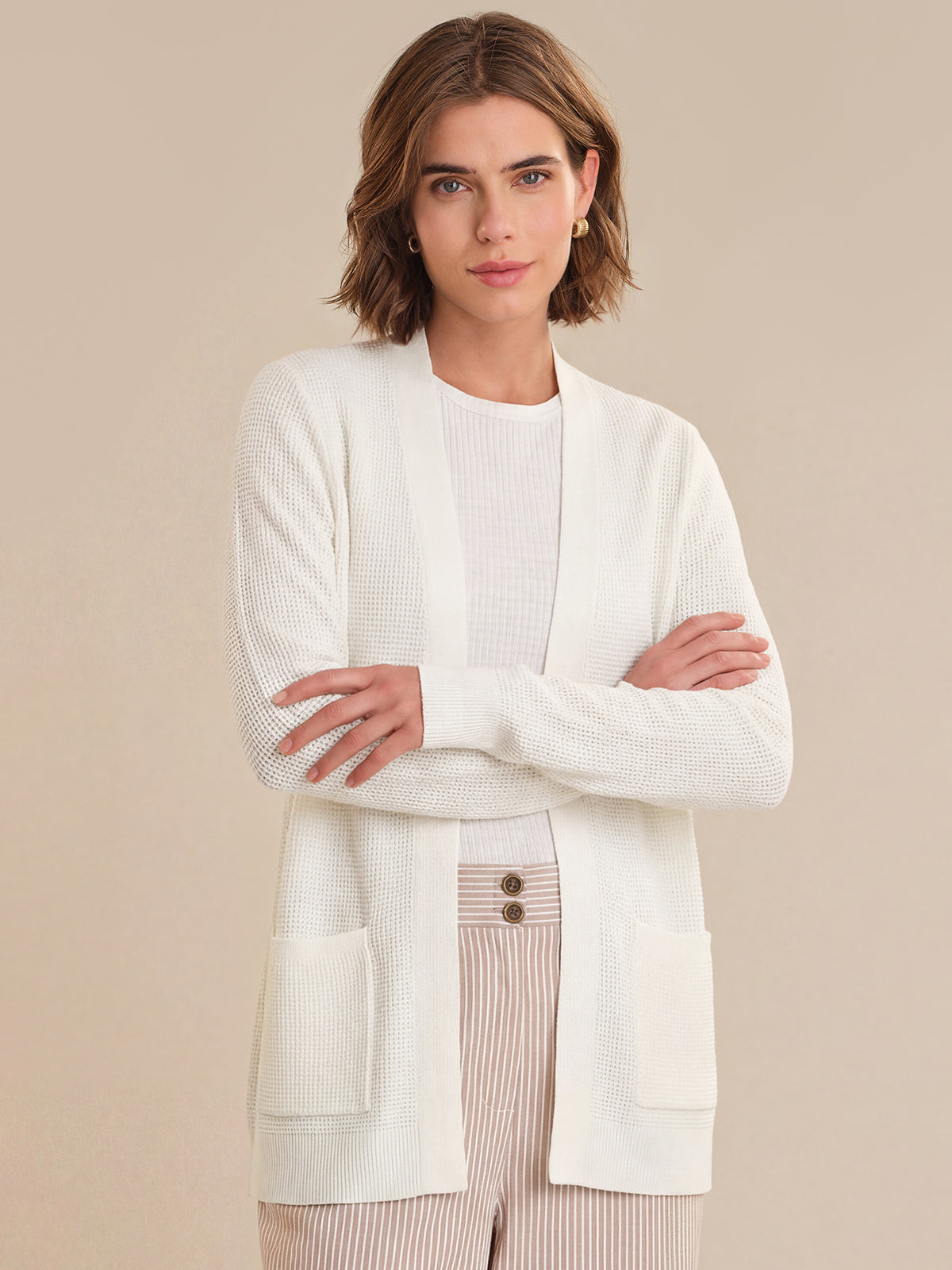 Woman wearing a white cardigan over a beige background
