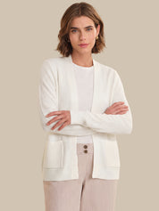 Woman wearing a white cardigan over a striped outfit on a beige background