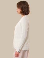 Woman wearing a white cardigan against a beige background