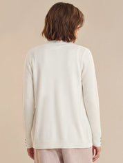 Person wearing a light-colored cardigan against a beige background