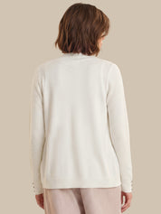 Person wearing a cream-colored cardigan on a beige background