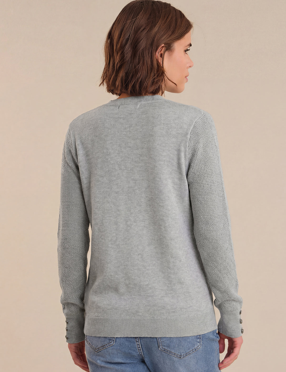 Person wearing a gray sweater with a neutral background