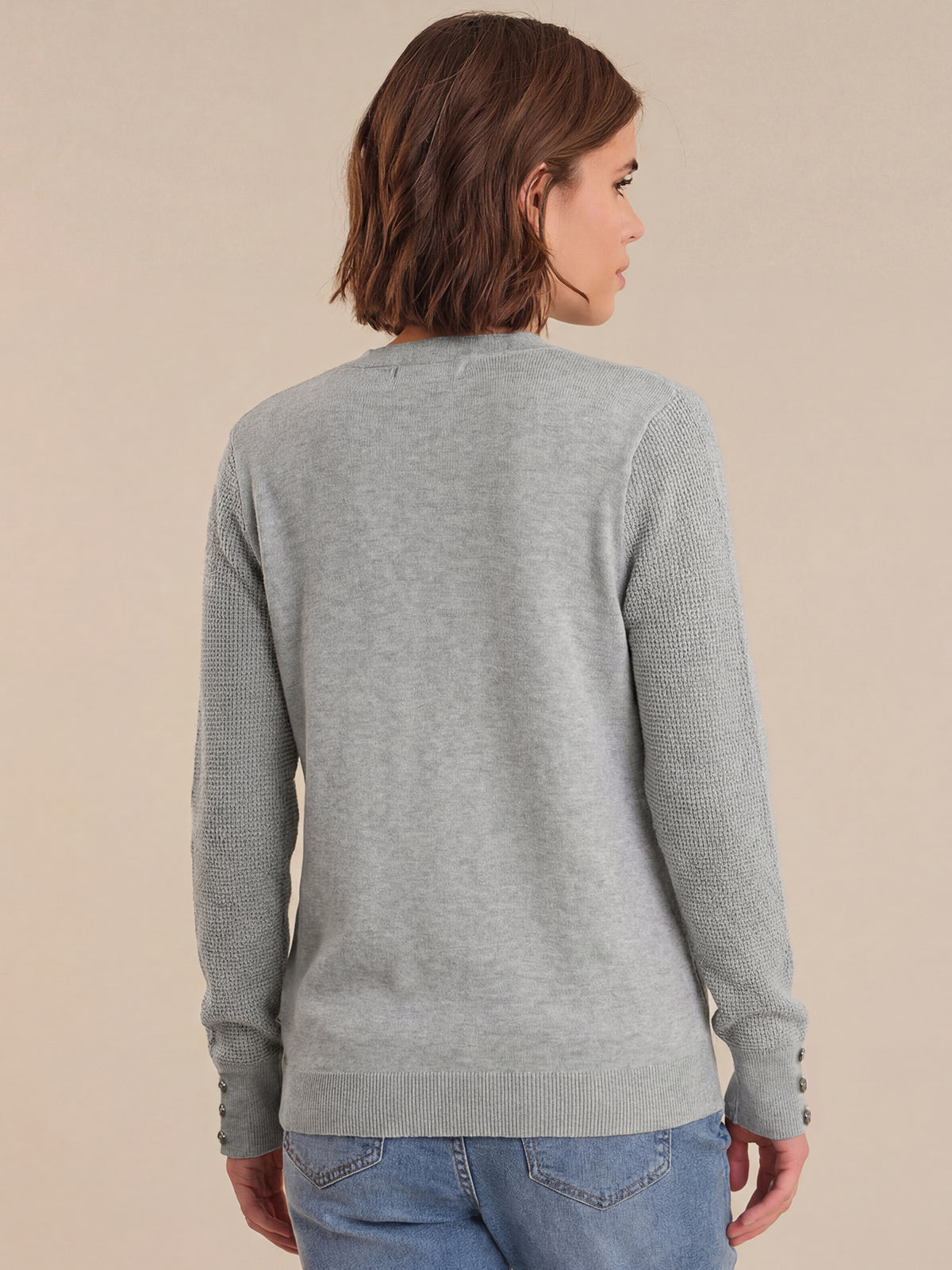 Person wearing a gray sweater with a neutral background