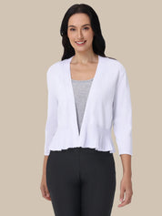 Woman wearing a white cardigan over a gray top and black pants on a beige background