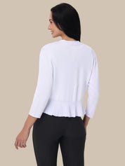 Woman wearing a white sweater and black pants on a beige background