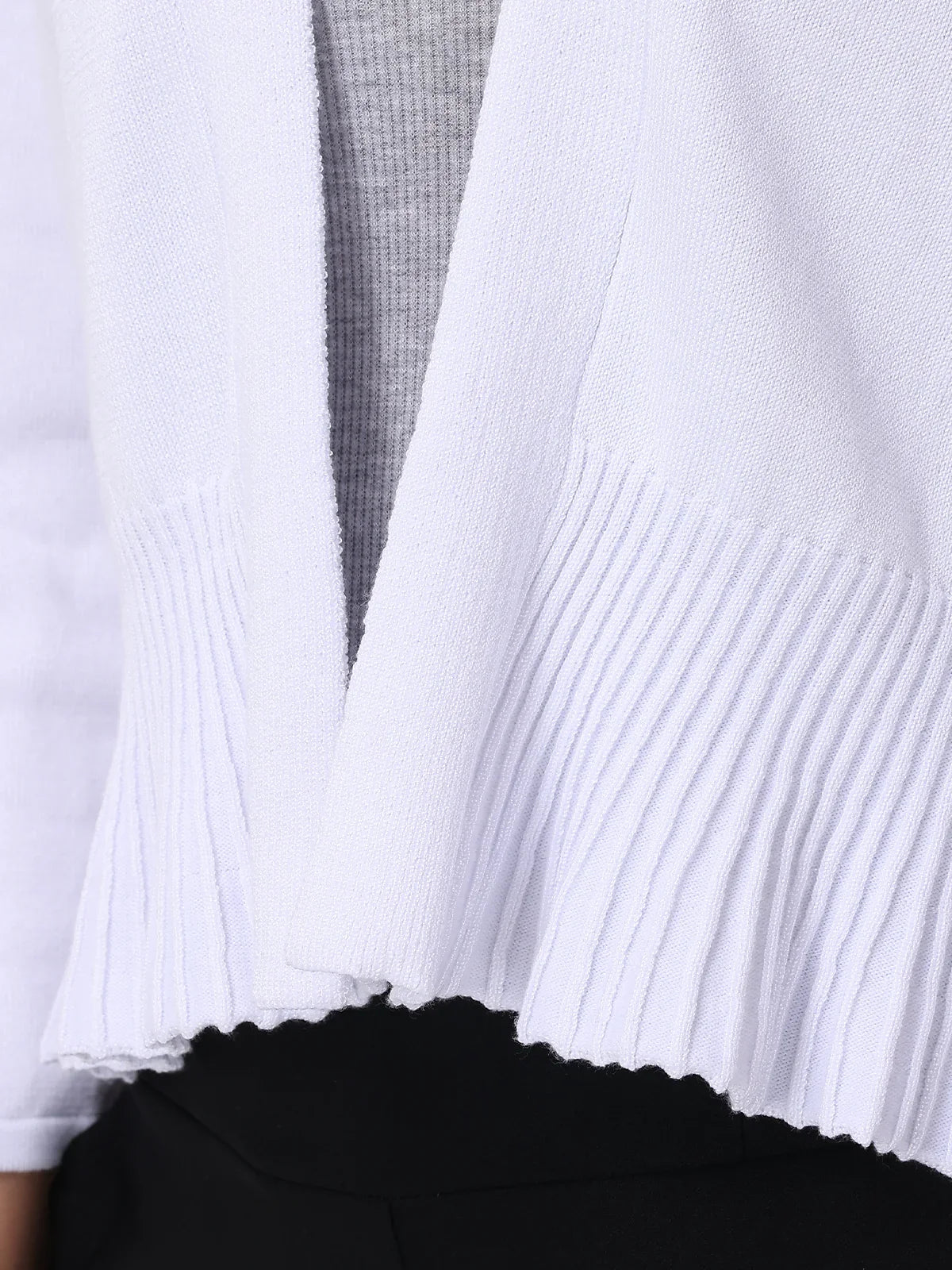 Close-up of a white ribbed knit garment with a black skirt underneath.