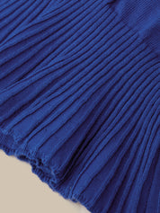 A close-up of a royal blue ribbed knit fabric, showing the detailed vertical pleats and texture, with a small portion of a light beige surface visible at the bottom left.
