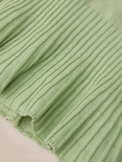 Close-up of a light sage green ribbed knit fabric with a frayed hem, showing the detailed texture and weave.