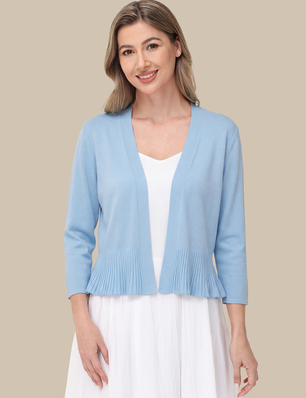Woman wearing a light blue cardigan over a white top and skirt on a beige background