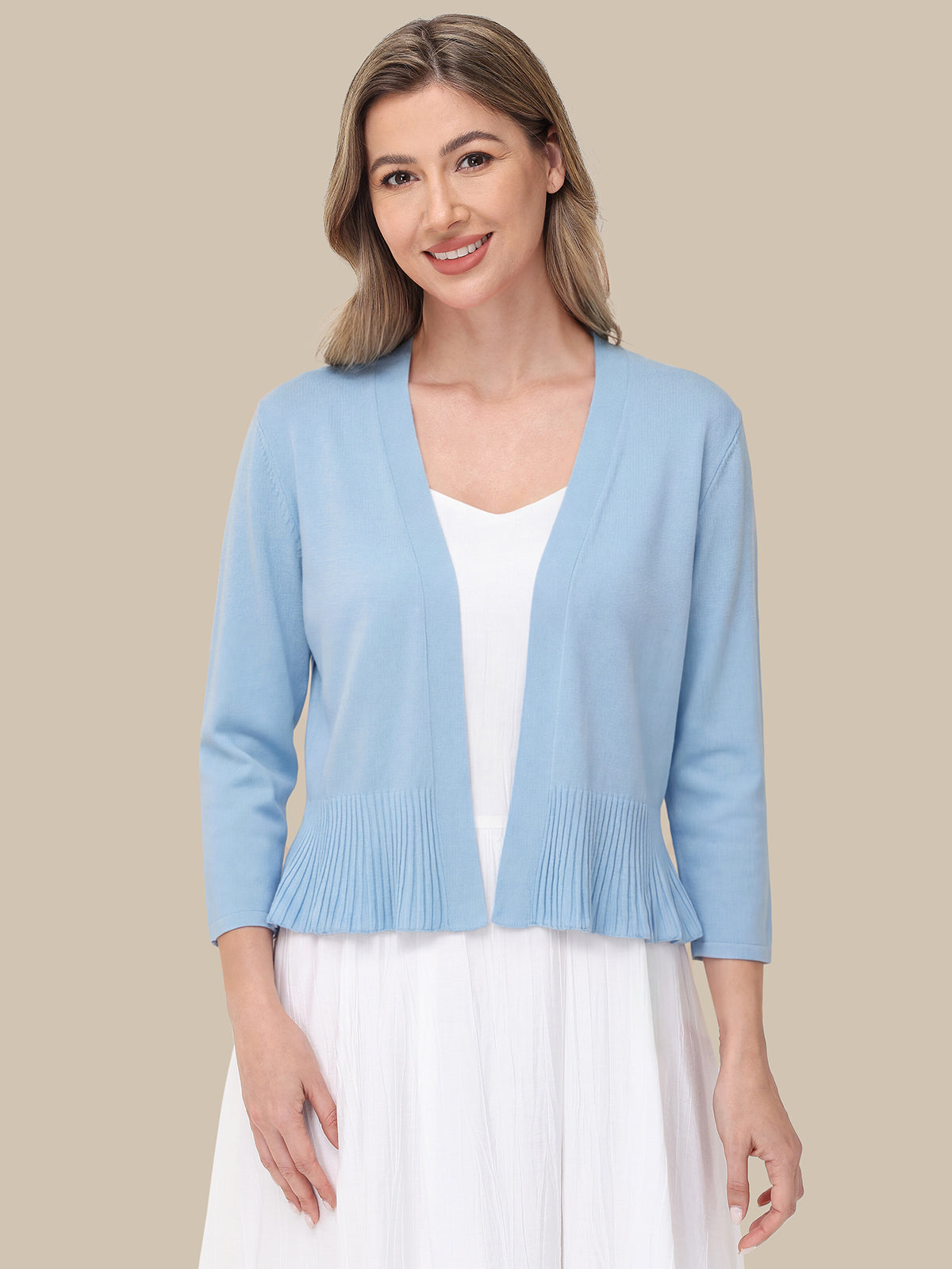 Woman wearing a light blue cardigan over a white top and skirt on a beige background