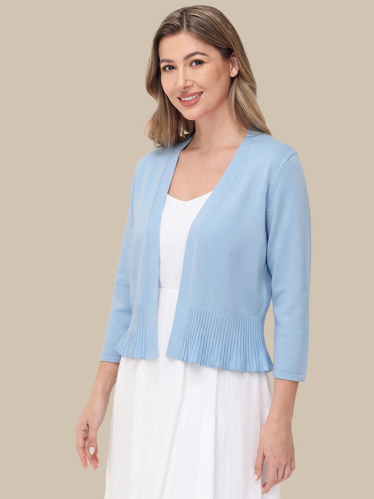 Woman wearing a light blue cardigan over a white top on a beige background