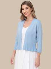 Woman wearing a light blue cardigan over a white top on a beige background