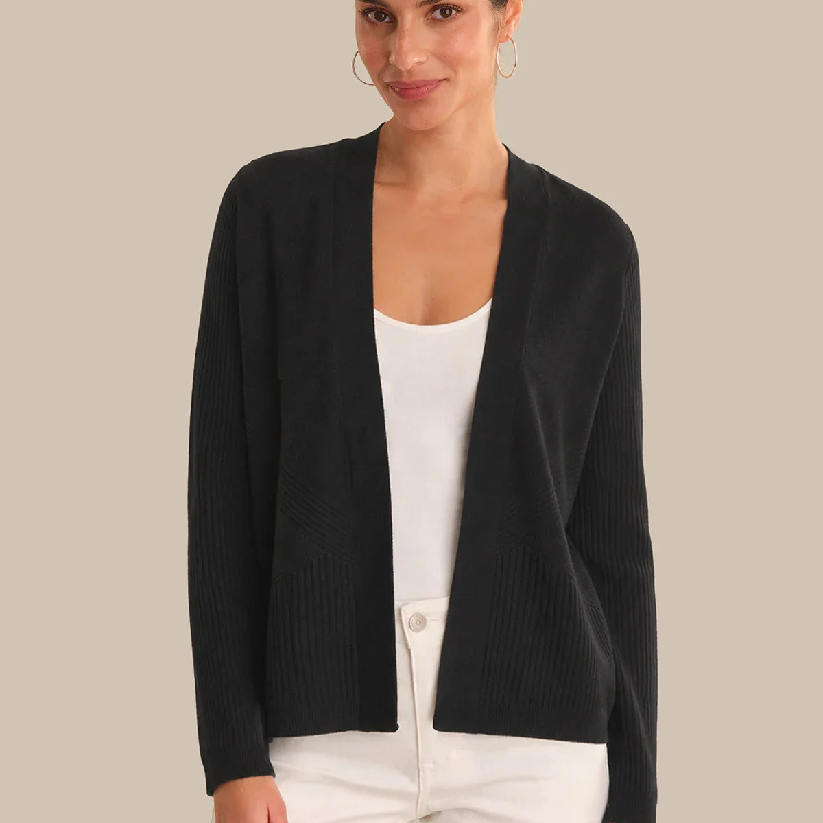 Woman wearing a black cardigan over a white top on a beige background