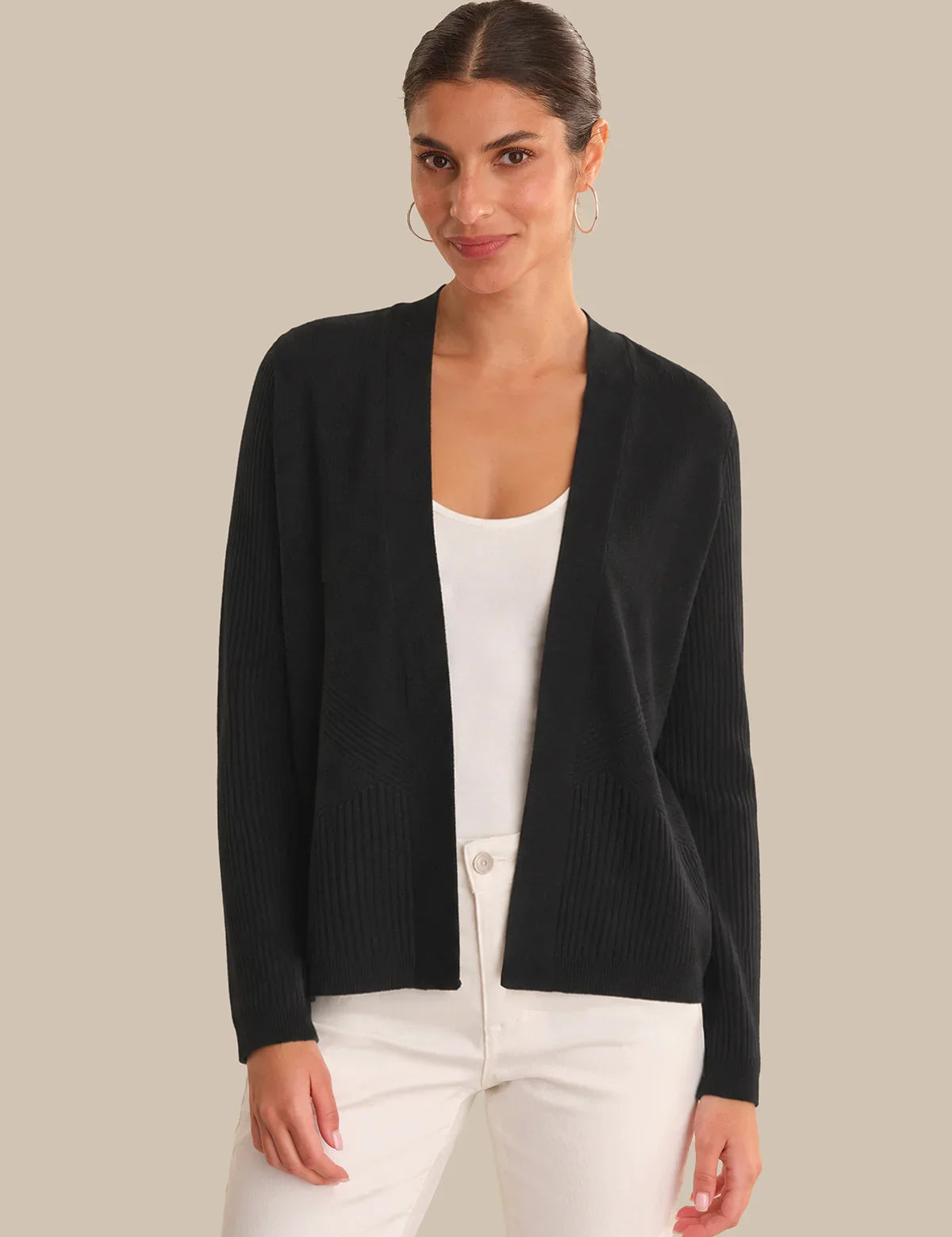 Woman wearing a black cardigan over a white top on a beige background