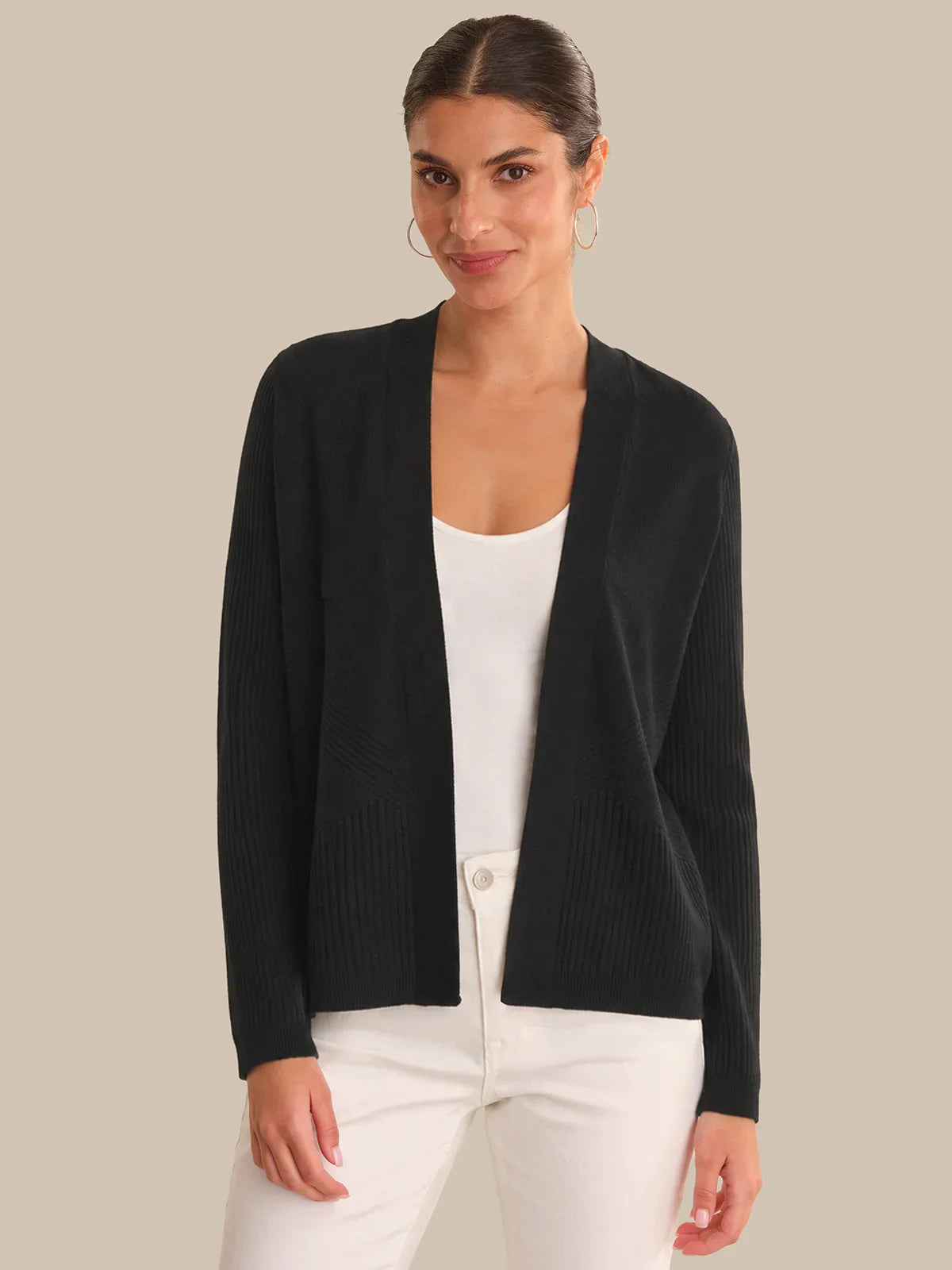 Woman wearing a black cardigan over a white top on a beige background