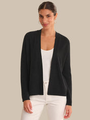 Woman wearing a black cardigan over a white top on a beige background