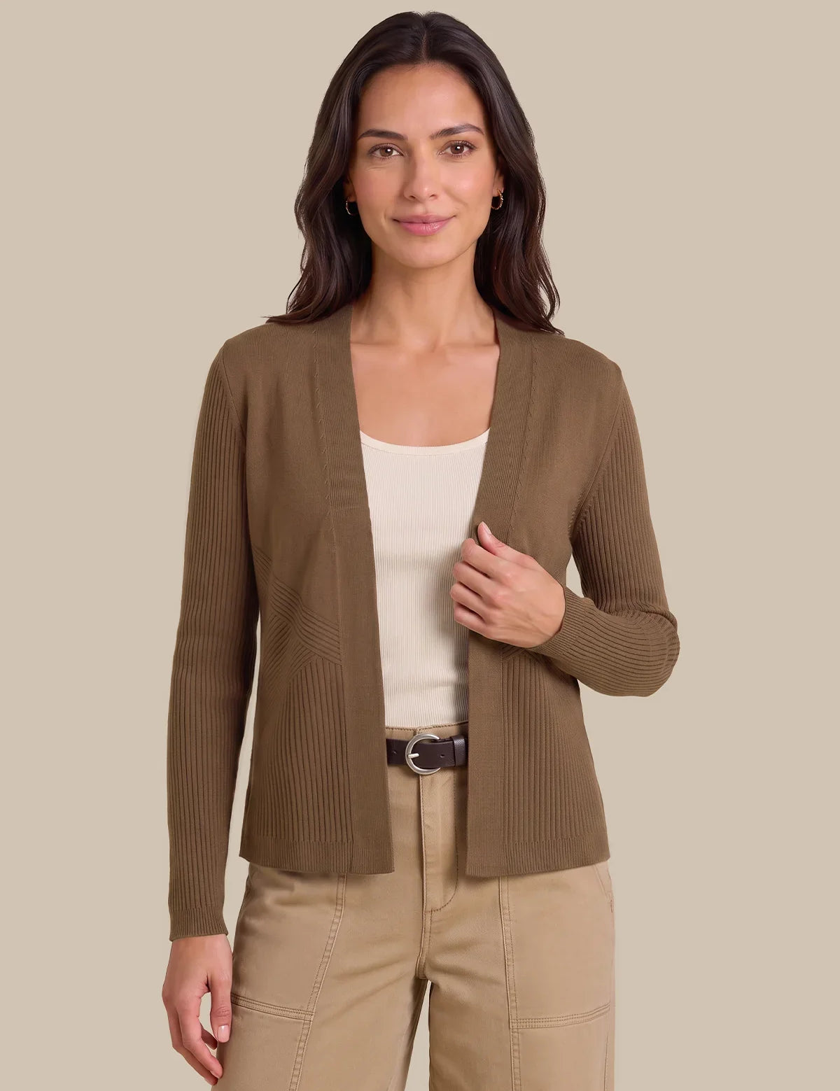 A woman modeling a ribbed open-front cardigan in taupe brown, worn over a cream tank top and beige pants, against a solid beige studio background.