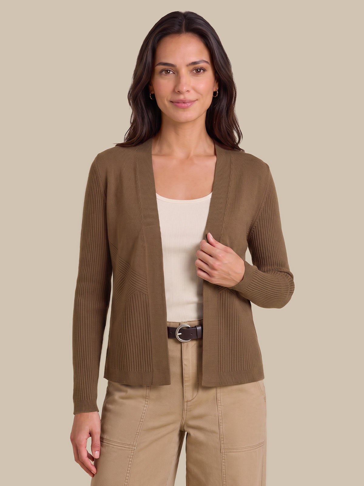 A woman modeling a ribbed open-front cardigan in taupe brown, worn over a cream tank top and beige pants, against a solid beige studio background.