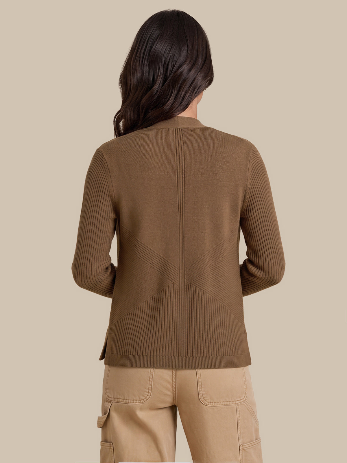 A woman shown from the back wearing a brown ribbed knit sweater and beige cargo pants against a solid beige studio background.