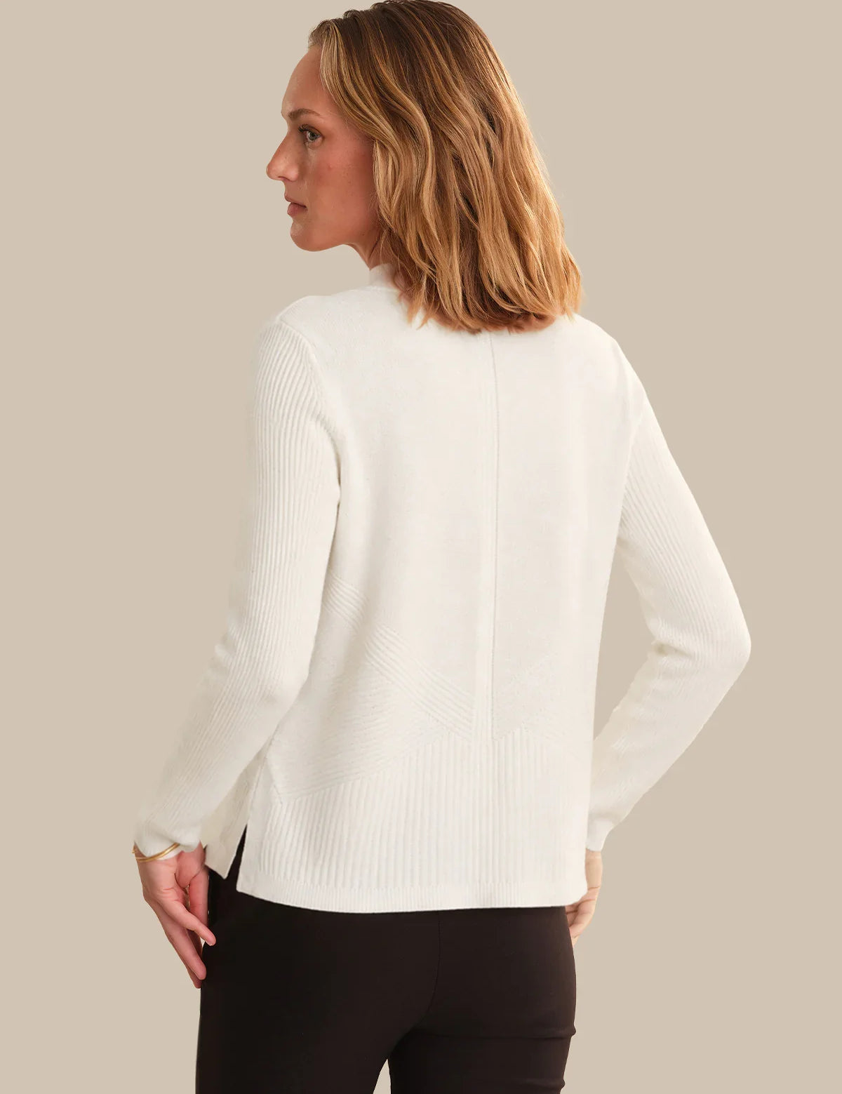 Woman wearing a white sweater against a beige background