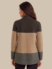 A woman shown from the back wearing a color-block knit cardigan with dark olive green, tan, and gray sections against a solid beige background.