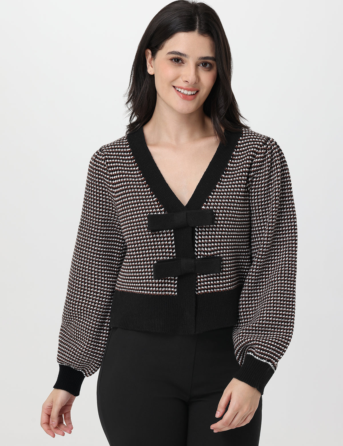 Woman wearing a chocolate and white patterned cardigan on a white background