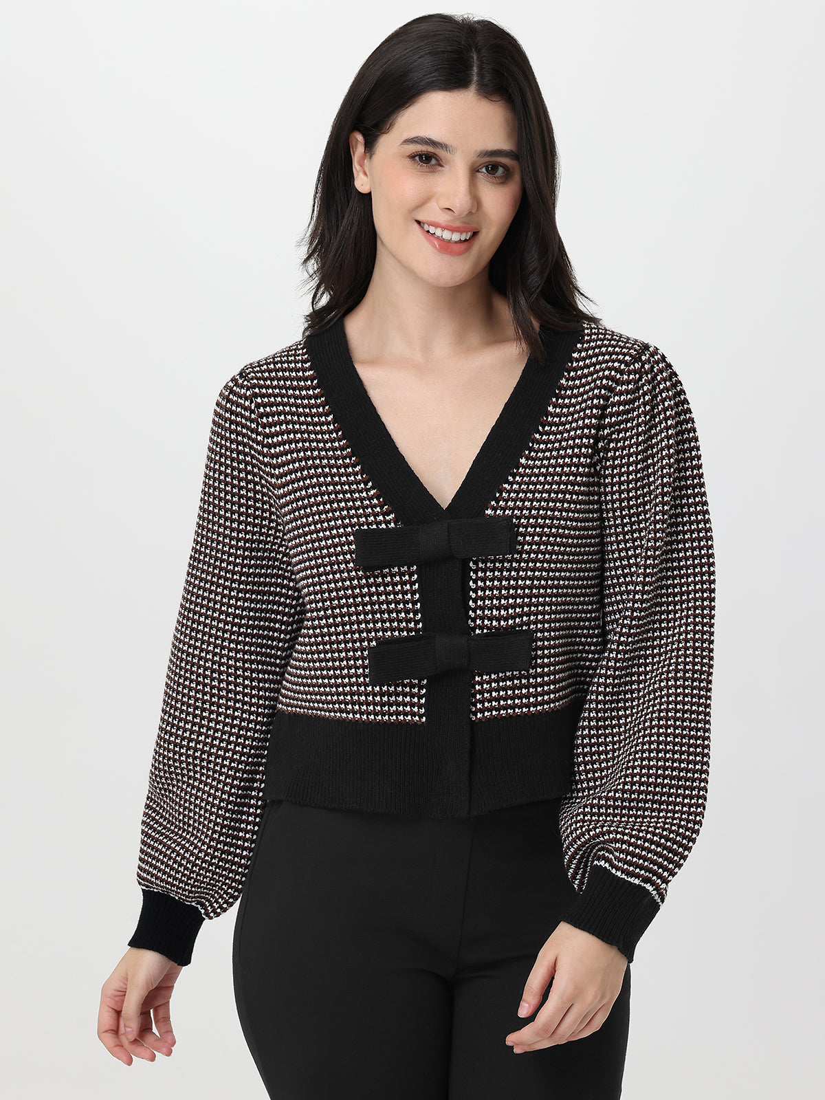 Woman wearing a chocolate and white patterned cardigan on a white background