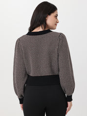 Woman wearing a chocolate and white patterned cardigan with long sleeves on a light gray background