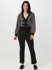 Woman wearing a chocolate and white patterned cardigan with a black skirt on a white background