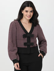 Woman wearing a patterned cardigan with deep garnet accents on a white background