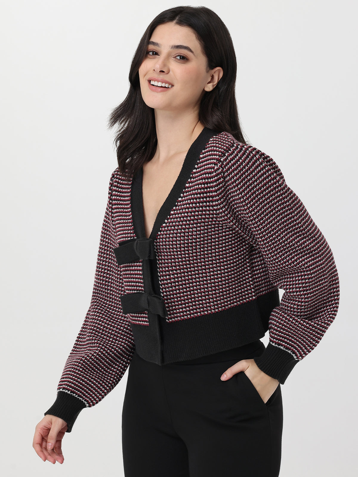 Woman wearing a patterned cardigan with a deep garnet accent on a white background
